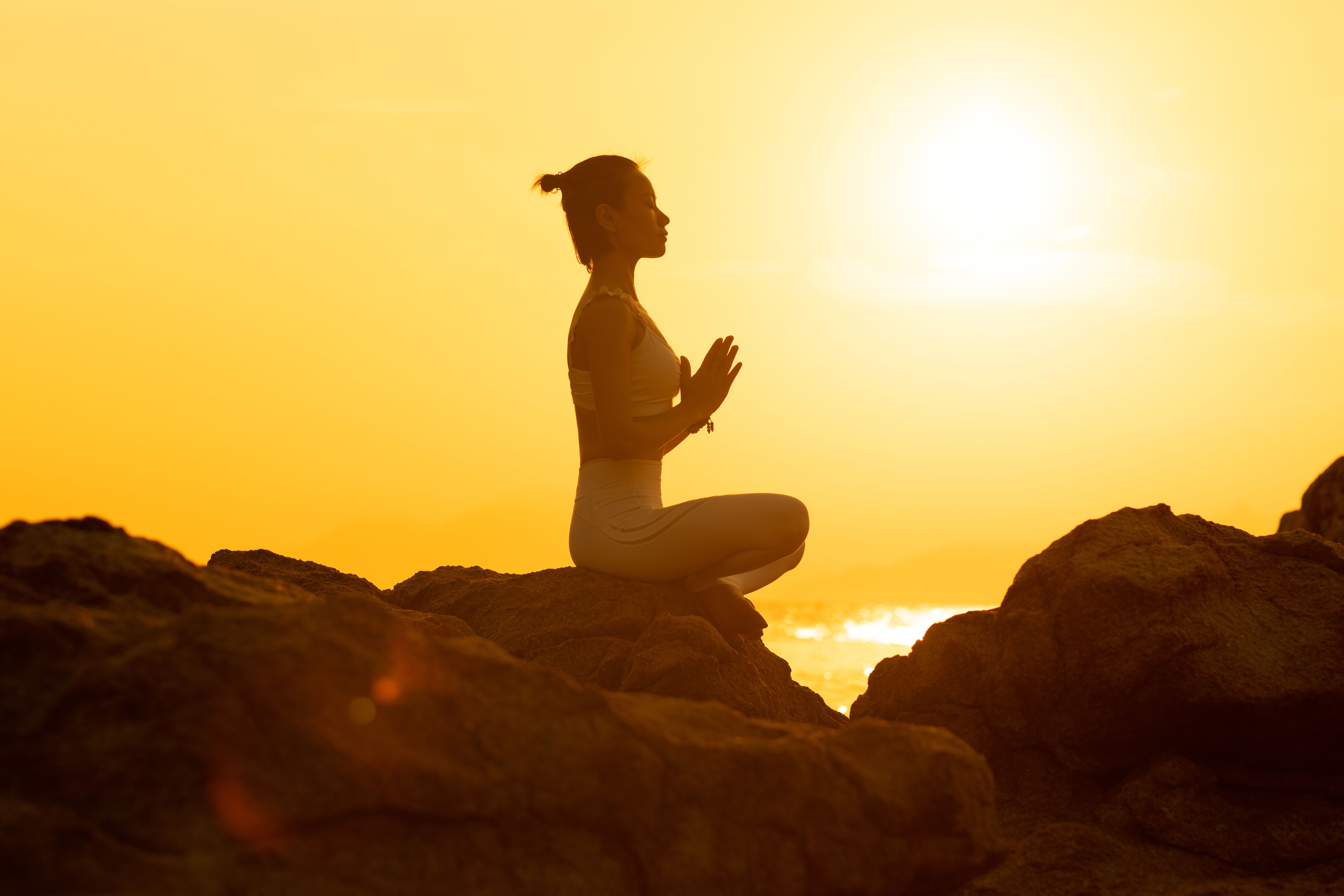 A person meditating at sunrise